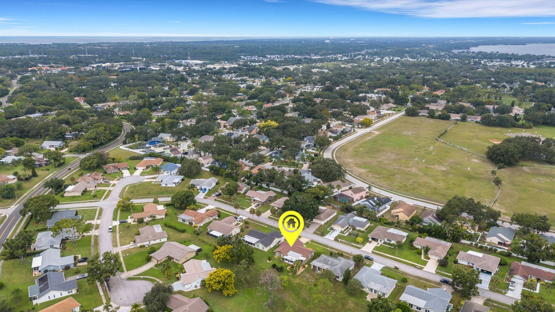 Magnifying glass over yellow house model surrounded by other colorful miniature houses on a map.