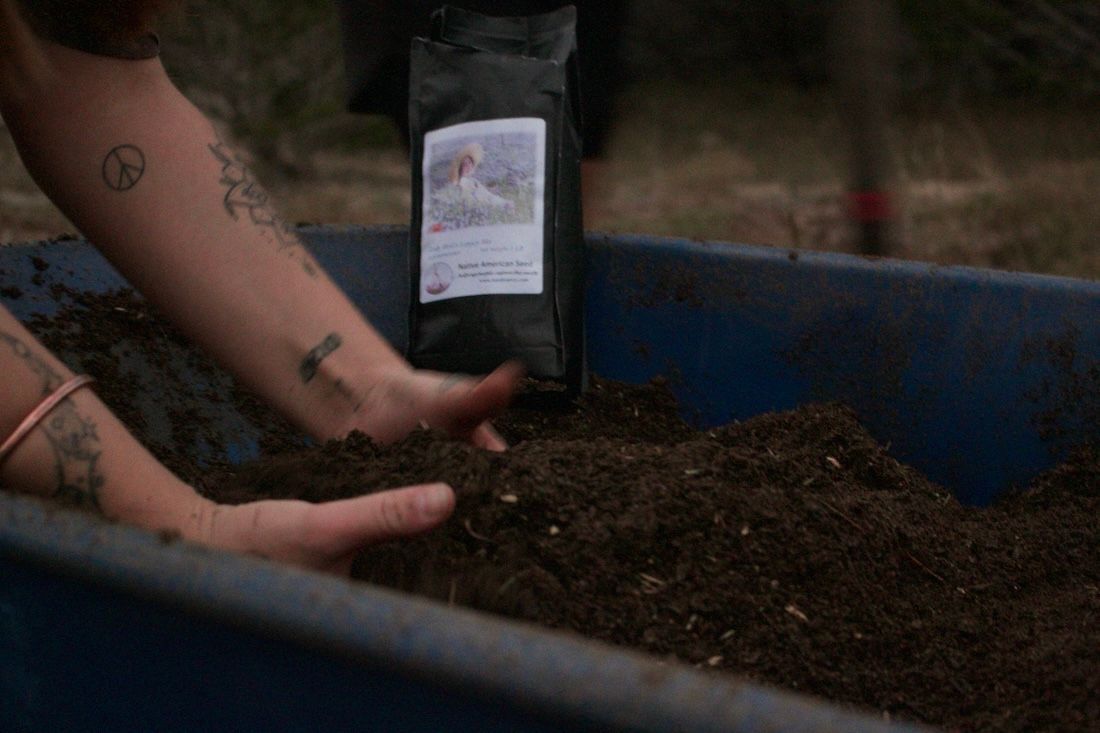 Hands mixing soil in a blue bin, with a bag of seed mix visible.