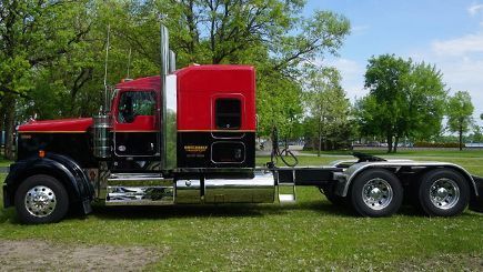 Red and black semi-truck parked on grass. The cab has a red top and black bottom with chrome details.