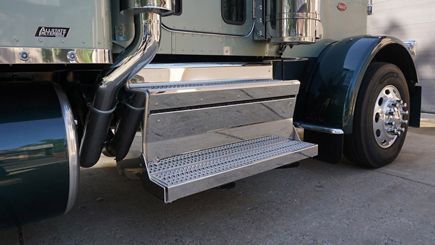 Shiny chrome steps on a teal semi-truck leading to the cabin and a black tire.