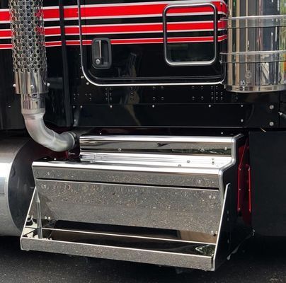 Shiny metal step box on a black semi-truck, with red and black stripes above.