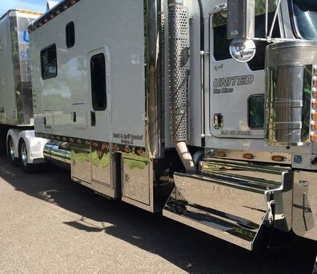White and chrome semi-truck with a sleeper cab parked on a road. 
