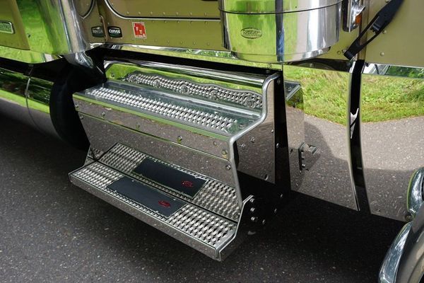 Shiny metal steps on a truck with black non-slip pads, outdoors.