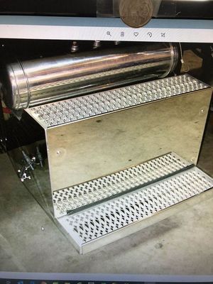 Shiny metal truck step with diamond plate on top and bottom, next to a silver cylinder.