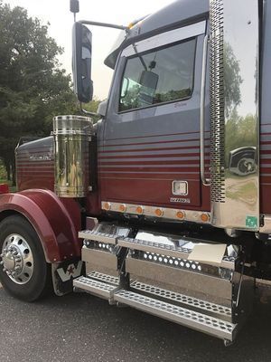 Red and gray semi-truck with chrome accents parked on asphalt.