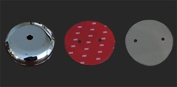 Three circular objects: chrome cover, red adhesive disc, and gray cover with holes.