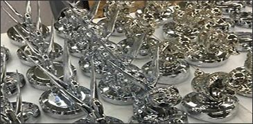 Shiny metal sculptures on display, various shapes and sizes, possibly ornaments.