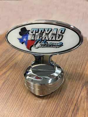 Chrome-based hood ornament with Texas flag graphic and the words 
