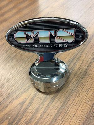 Chrome CTS Castiac Truck Supply emblem on a wooden surface.