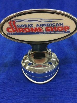 Chrome shop emblem with logo on a blue surface.