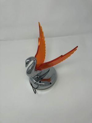 Chrome swan car hood ornament with orange wings.