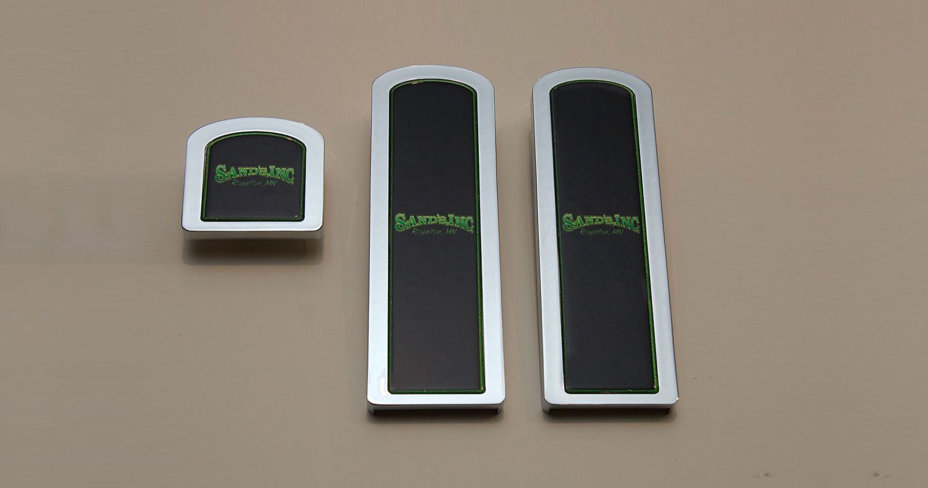 Three rectangular black and silver stickers. Green text, 