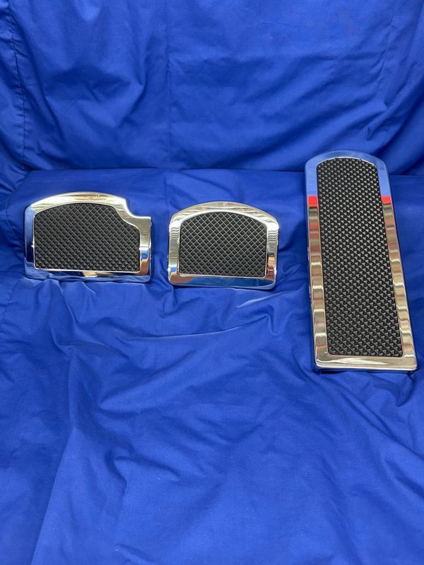 Chrome foot pedal set with black textured inserts, on blue background.