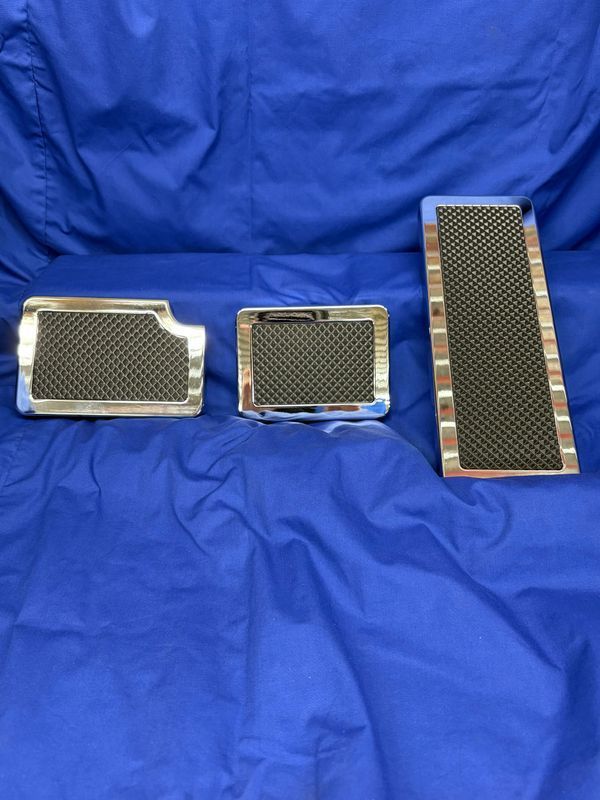 Three chromed metal and mesh vehicle floor mats on blue fabric.