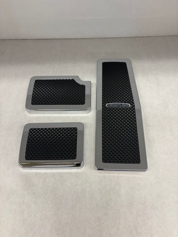 Chrome and black car pedal covers on a white surface.