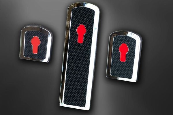 Chrome car pedal covers with red keyhole shapes on a black background.