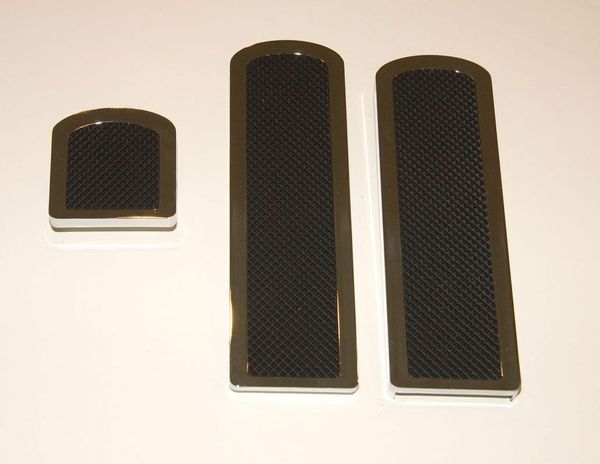 Three dark-colored car pedal covers with a textured, rectangular center.