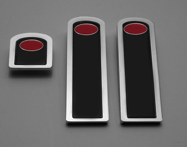 Three chrome and black car emblems with red oval accents.