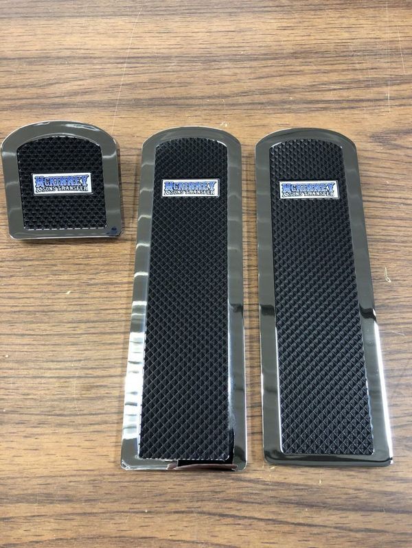 Three black and silver car pedal covers with the word 