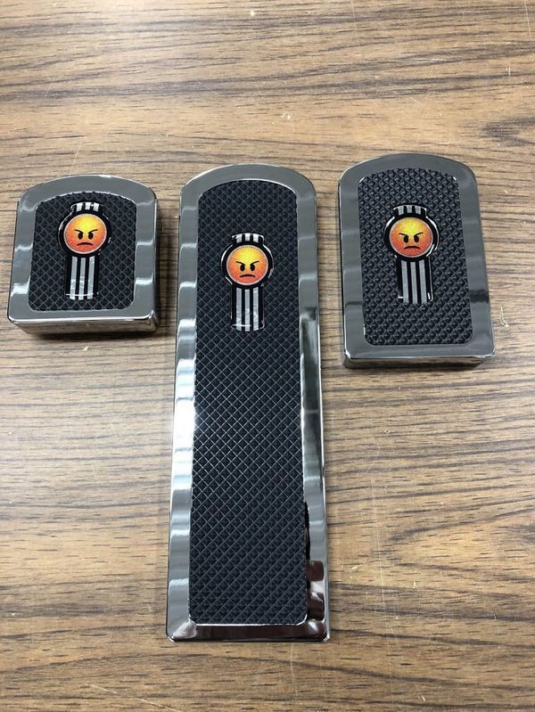 Three Kenworth truck emblem accessories, chrome trim, black textured center, and angry face logo.