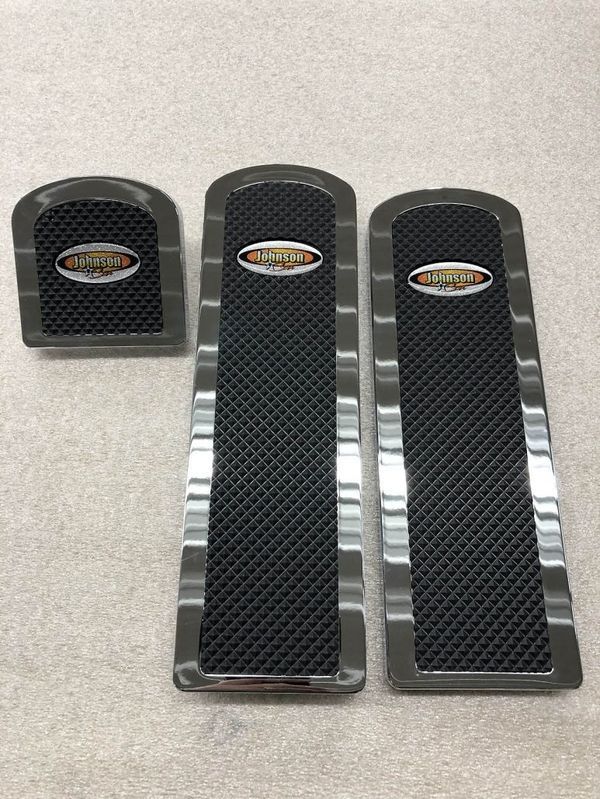 Set of three metal and black floor mats, likely for a vehicle. Each has a logo.