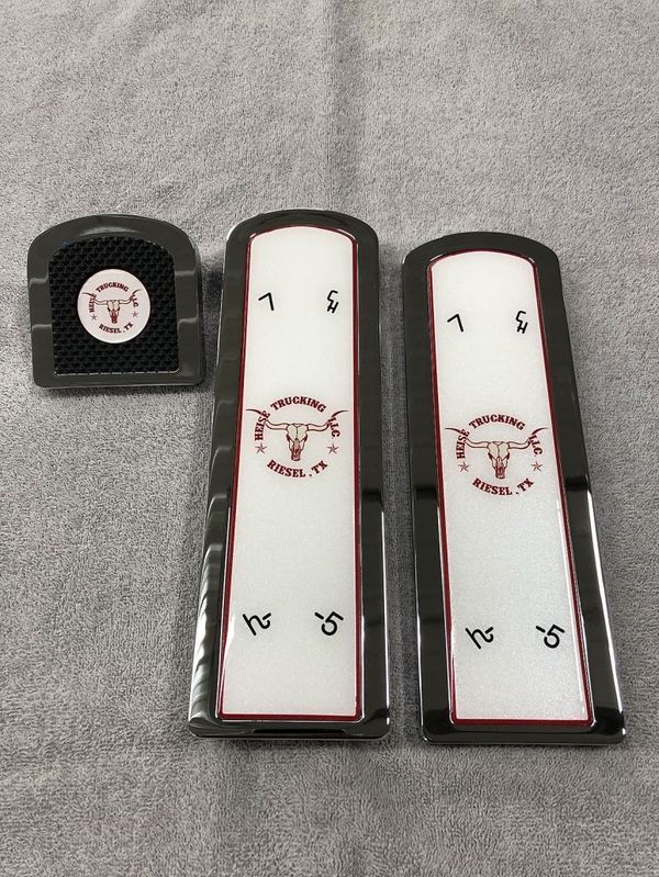 Set of three custom car accessories with a bull logo and text, on a gray surface.