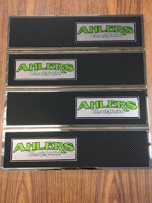 Four black rectangular Ahlers sign plates with green and silver logos on wood.