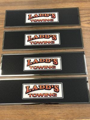 Four black and silver Ladd's Towing bar mats with logo in white, orange, and red.