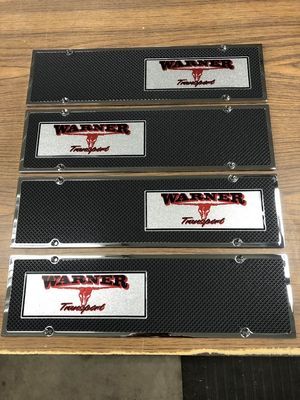Four Warner Transport license plates with silver and black carbon fiber design.