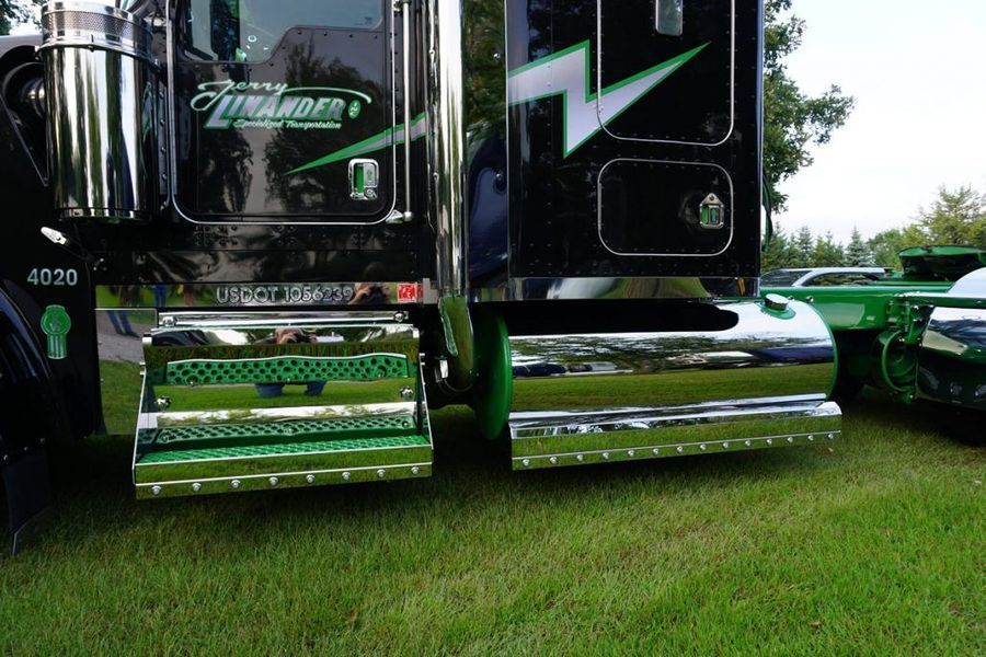 Close-up of a black truck with chrome detailing and green accents parked on grass.