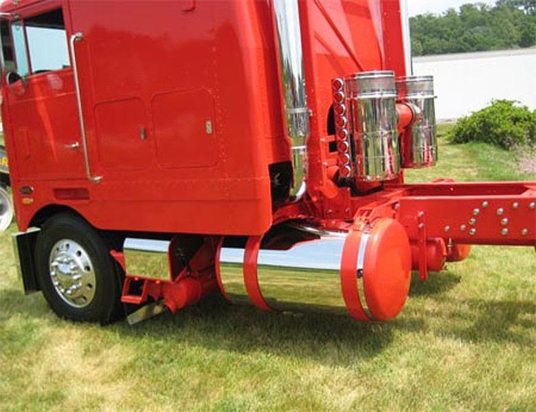 Red semi-truck cab with chrome details and stacks on green grass.