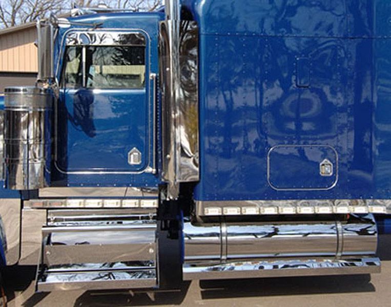 Blue semi-truck cab with chrome details, parked outdoors on a sunny day.