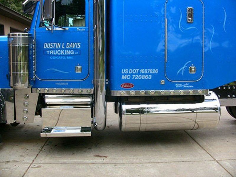 Blue semi-truck with chrome details parked on a concrete surface; details include lettering 