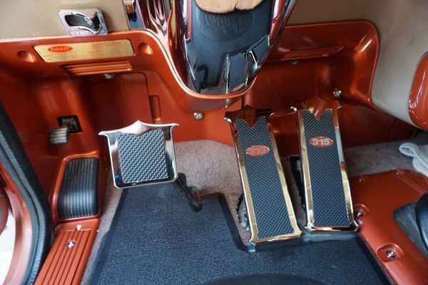 Interior car detail: pedals with custom gold trim, in an orange and brown setting.