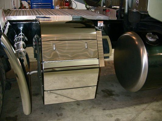 Chrome box mounted on the side of a semi-truck with a tire visible.