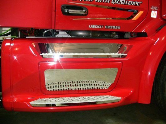Red semi-truck's bumper with chrome accents, step, and grille; US DOT number visible.
