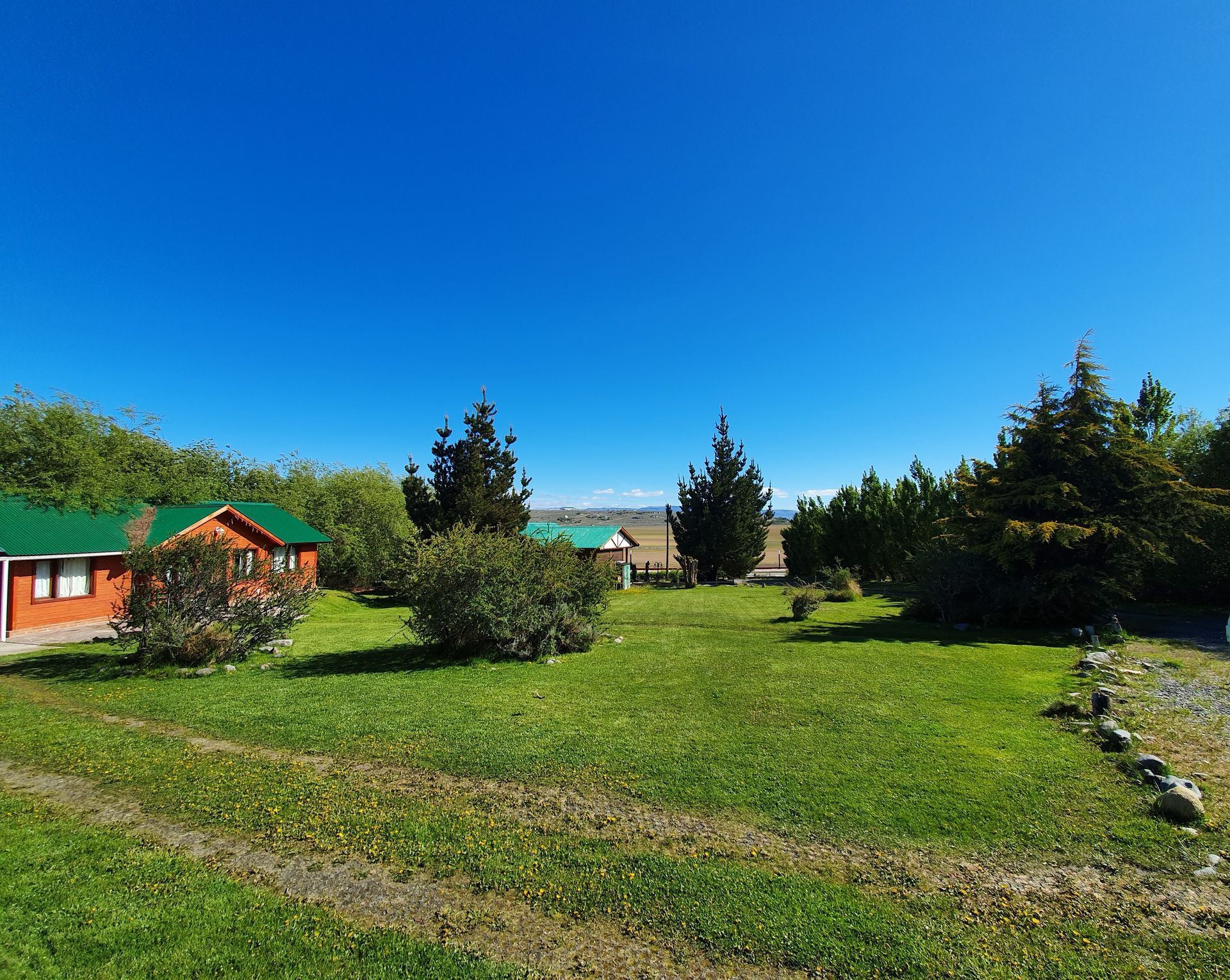 Un exuberante campo verde con algunas casas al fondo.