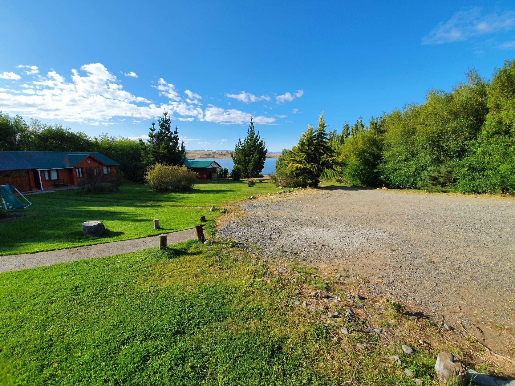 Un camino de tierra que conduce a una casa en medio de un exuberante campo verde.