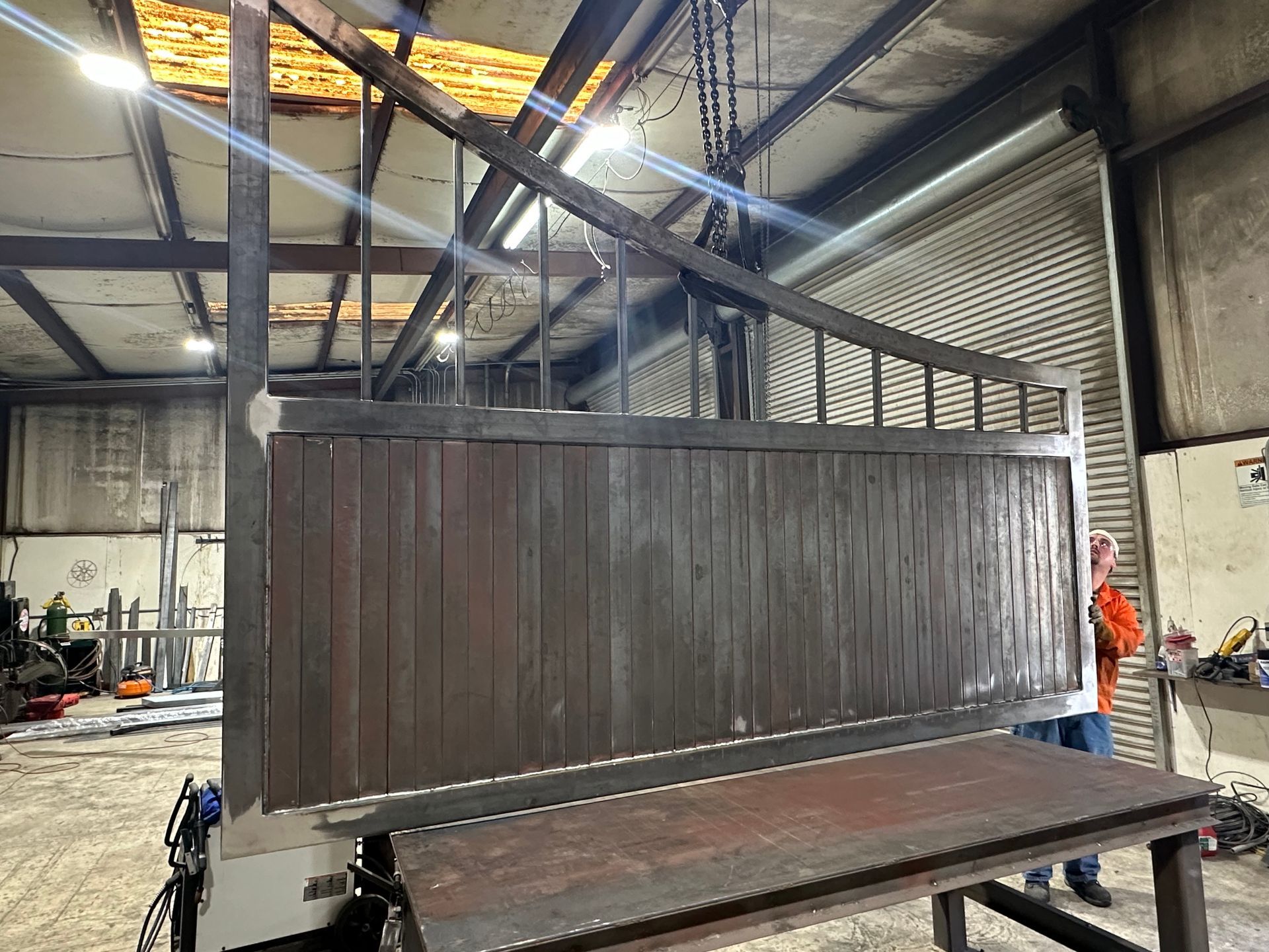 Large dark wooden crate or panel on a metal platform inside an industrial warehouse