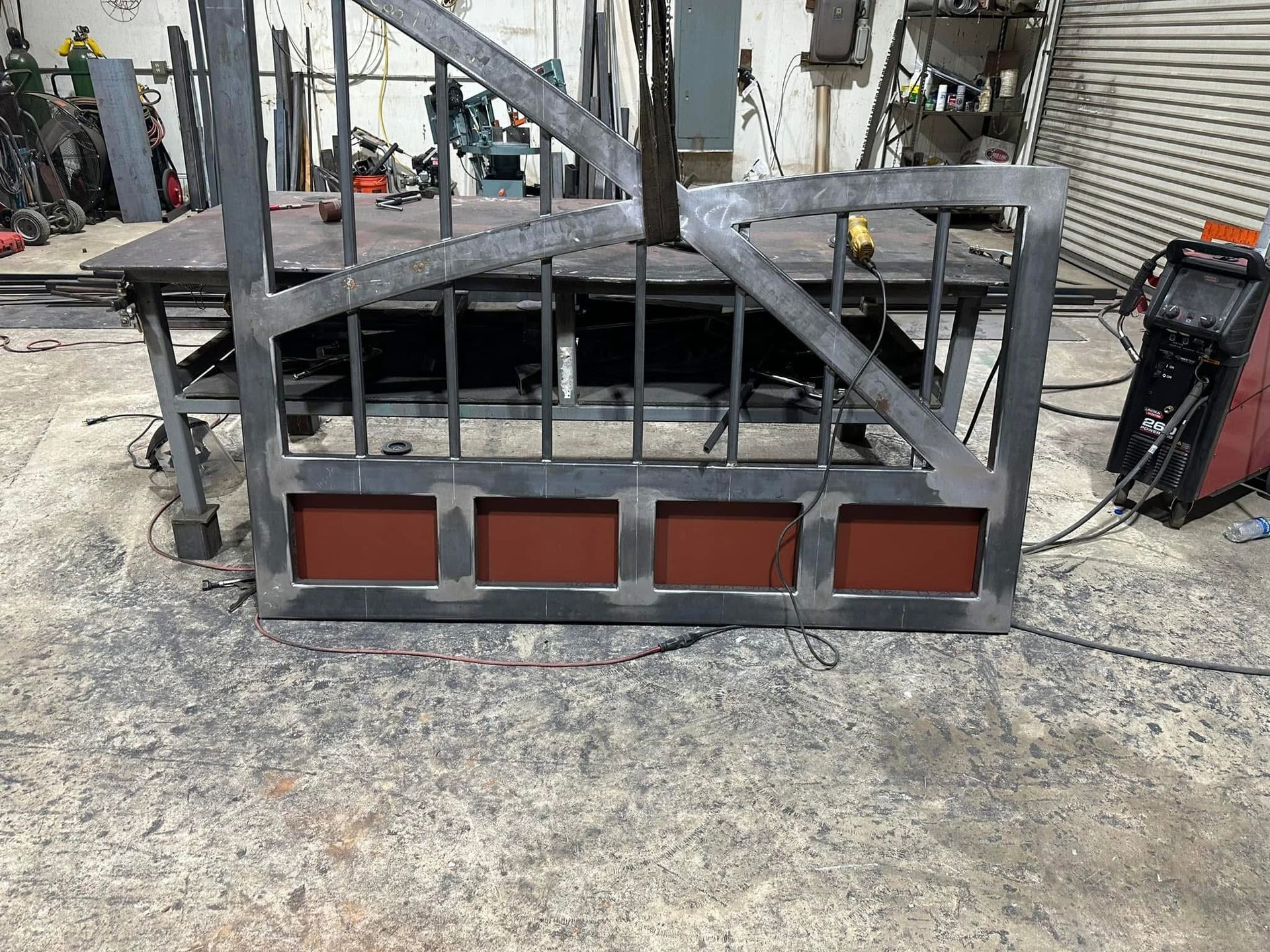 Broken metal barricade lying on concrete sidewalk beside a building, with a bent frame and red panels