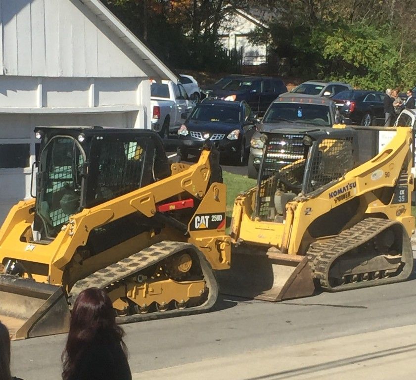 Two caterpillar tractors are parked on the side of the road