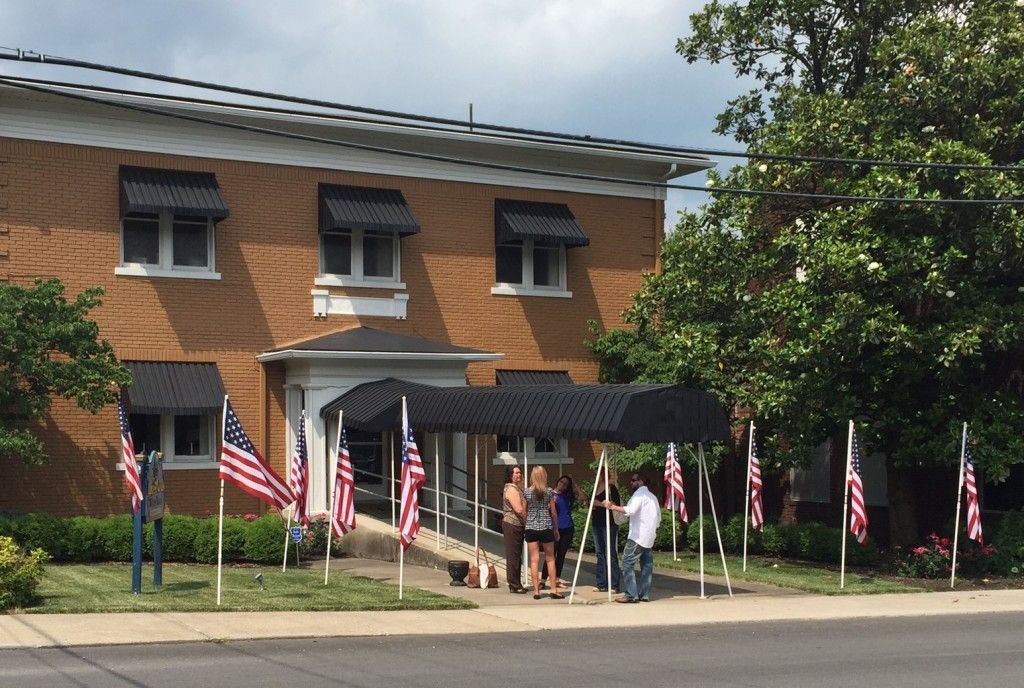 A group of people standing outside of a building with american flags