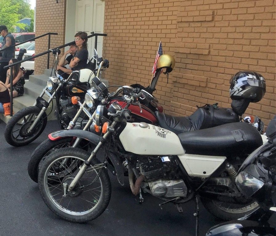 Several motorcycles are parked in front of a brick building