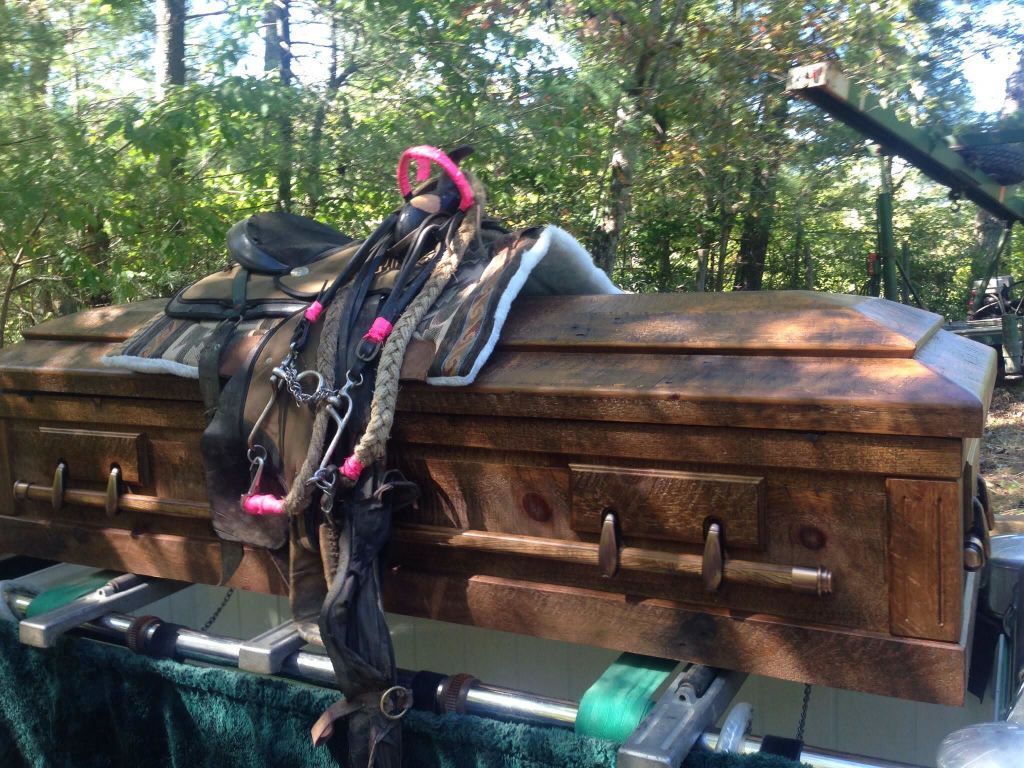 A wooden coffin with a saddle on top of it