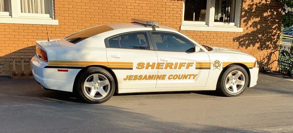 A sheriff 's car is parked in front of a brick building