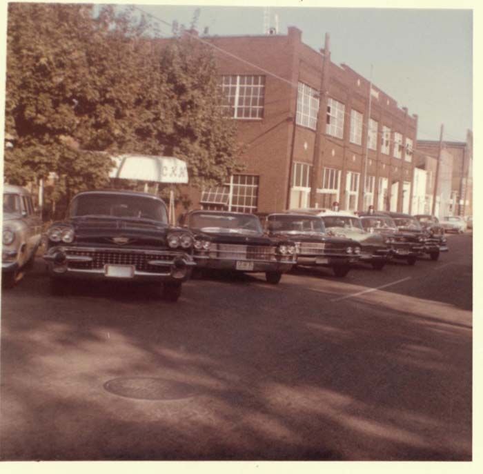 A row of old cars are parked on the side of the road