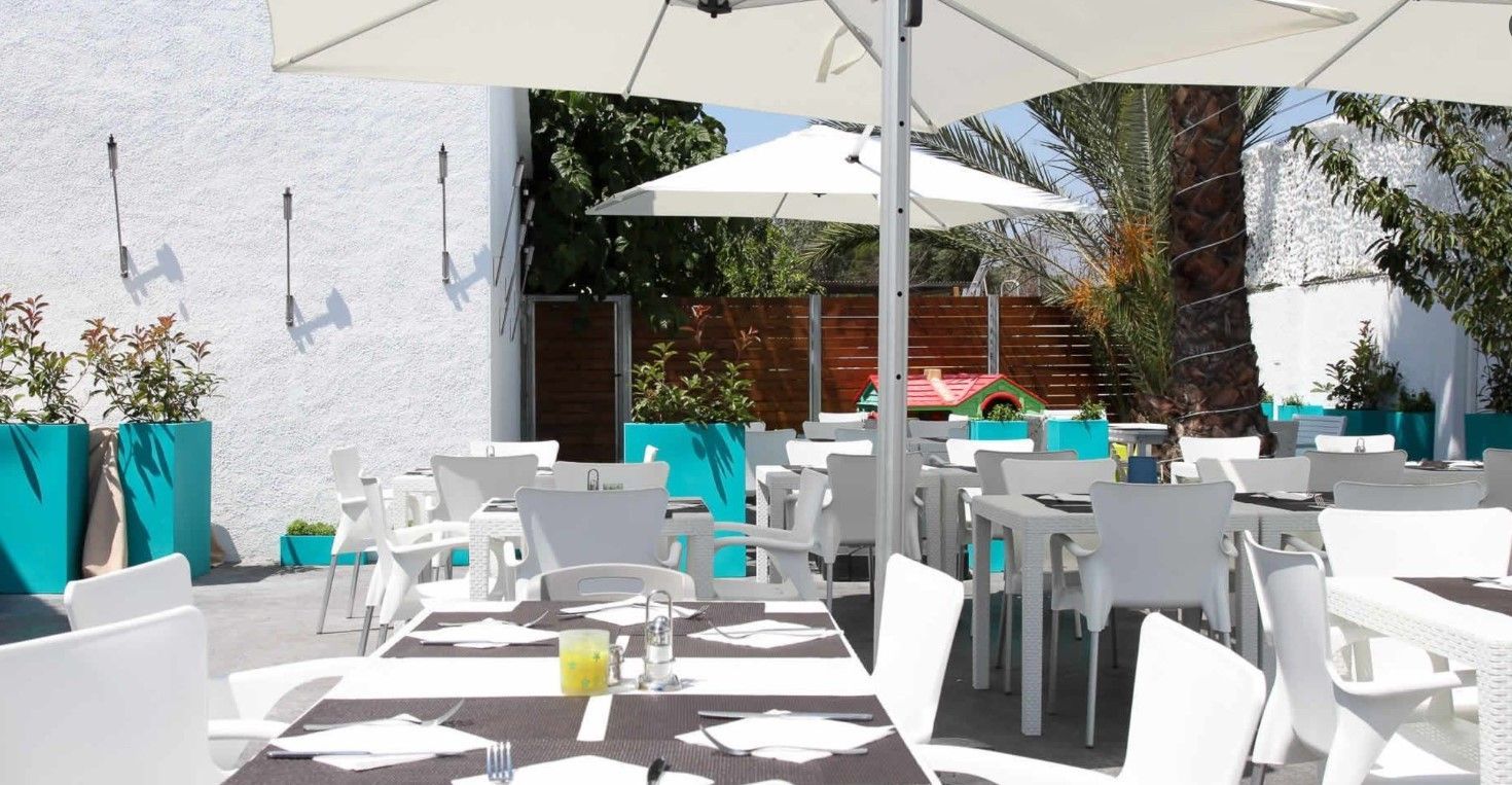 A restaurant with white tables and chairs and white umbrellas