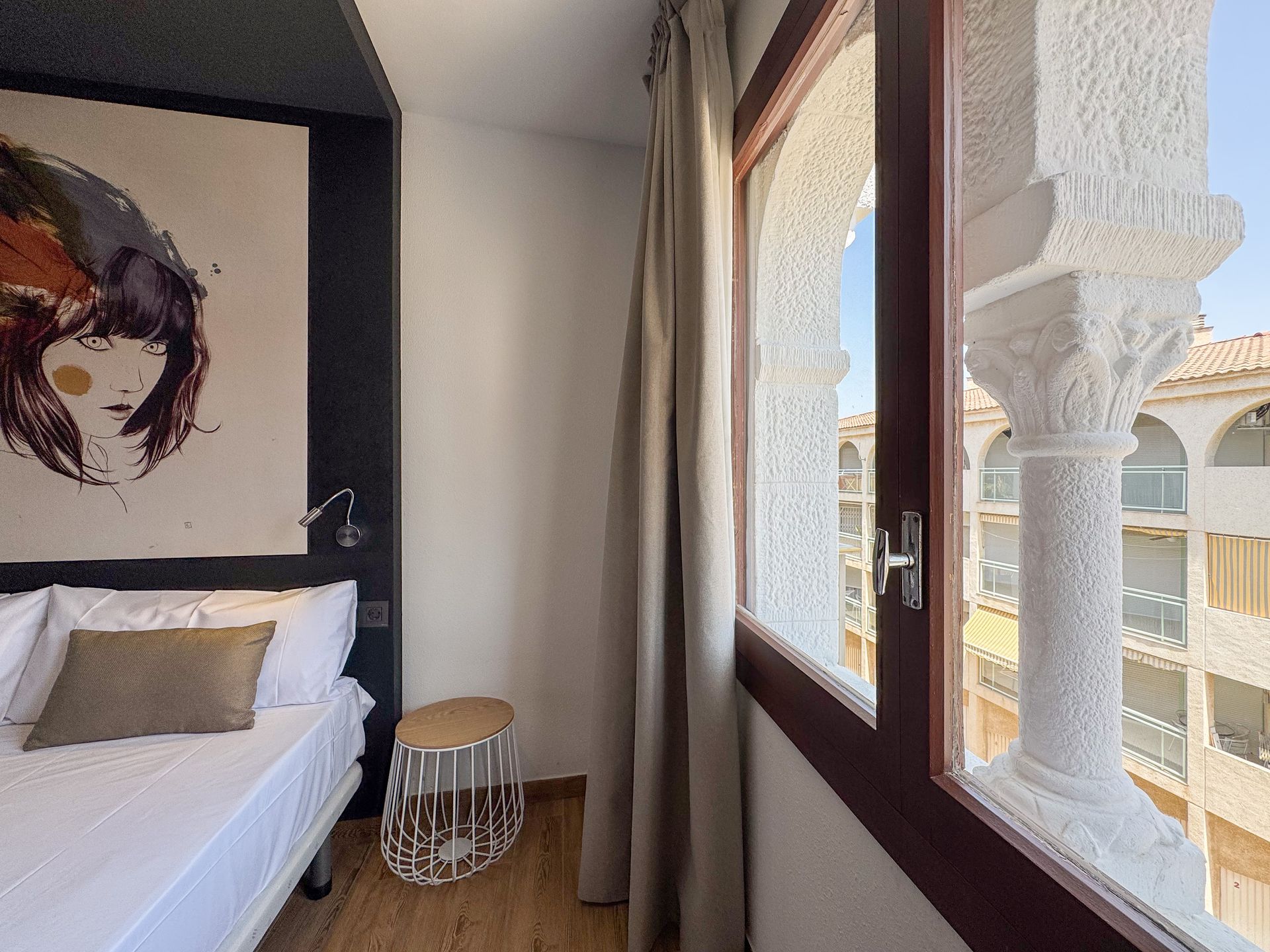 Un dormitorio con una gran ventana y un cuadro en la pared.