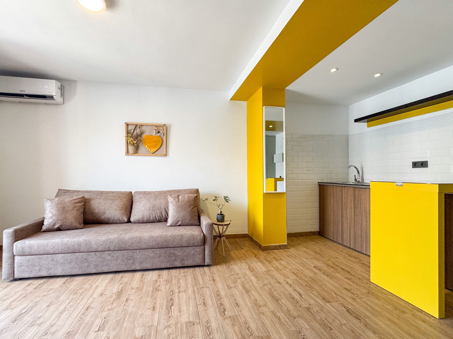 Una sala de estar con un sofá y una cocina al fondo.