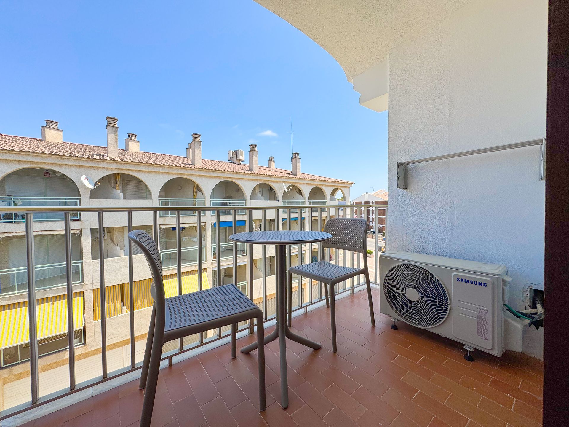 Un balcón con mesa y sillas y aire acondicionado.
